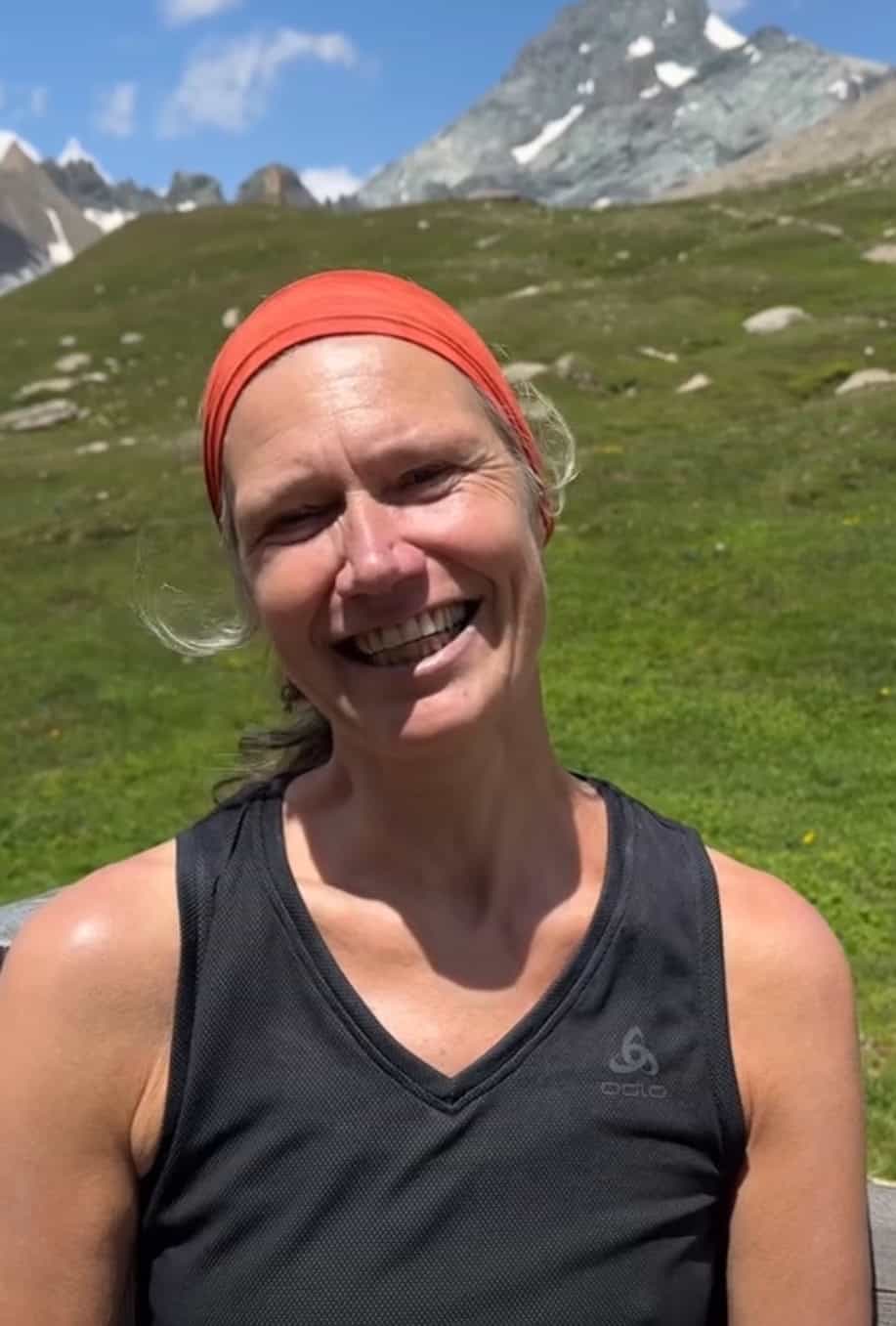 Frau mit orangener Haube im Wind lächelnd