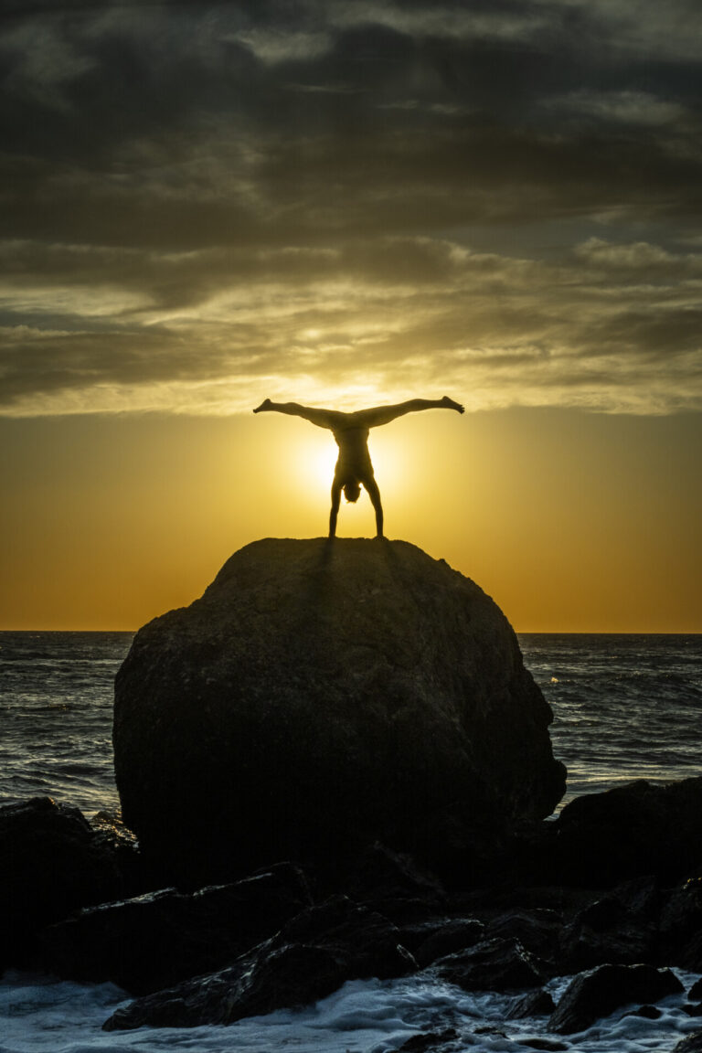 Vicki im Handstand auf einem großen Felsen im Meer